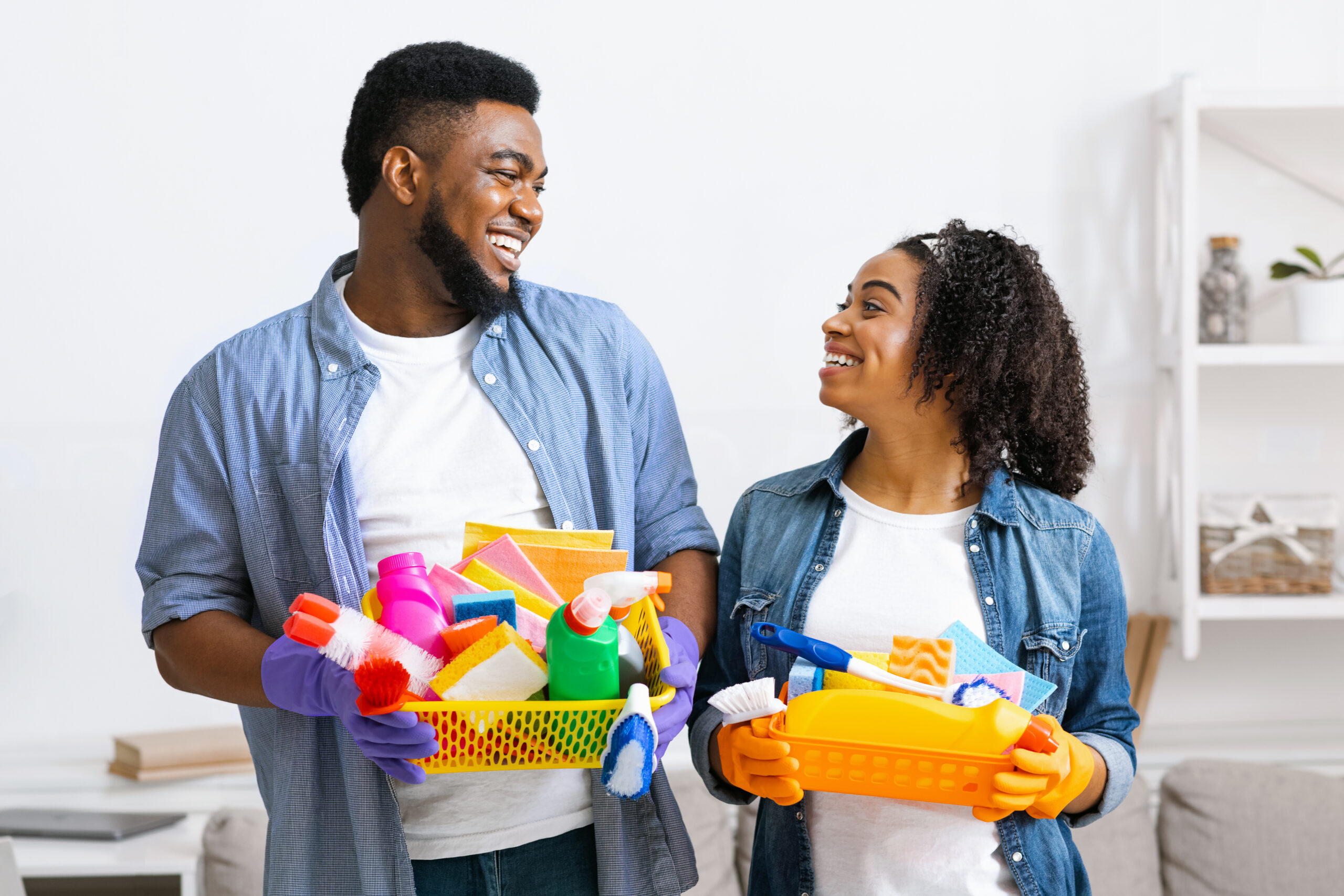 Big Cleaning Day. Smiling Black Couple Holding Containers With Household Tools
