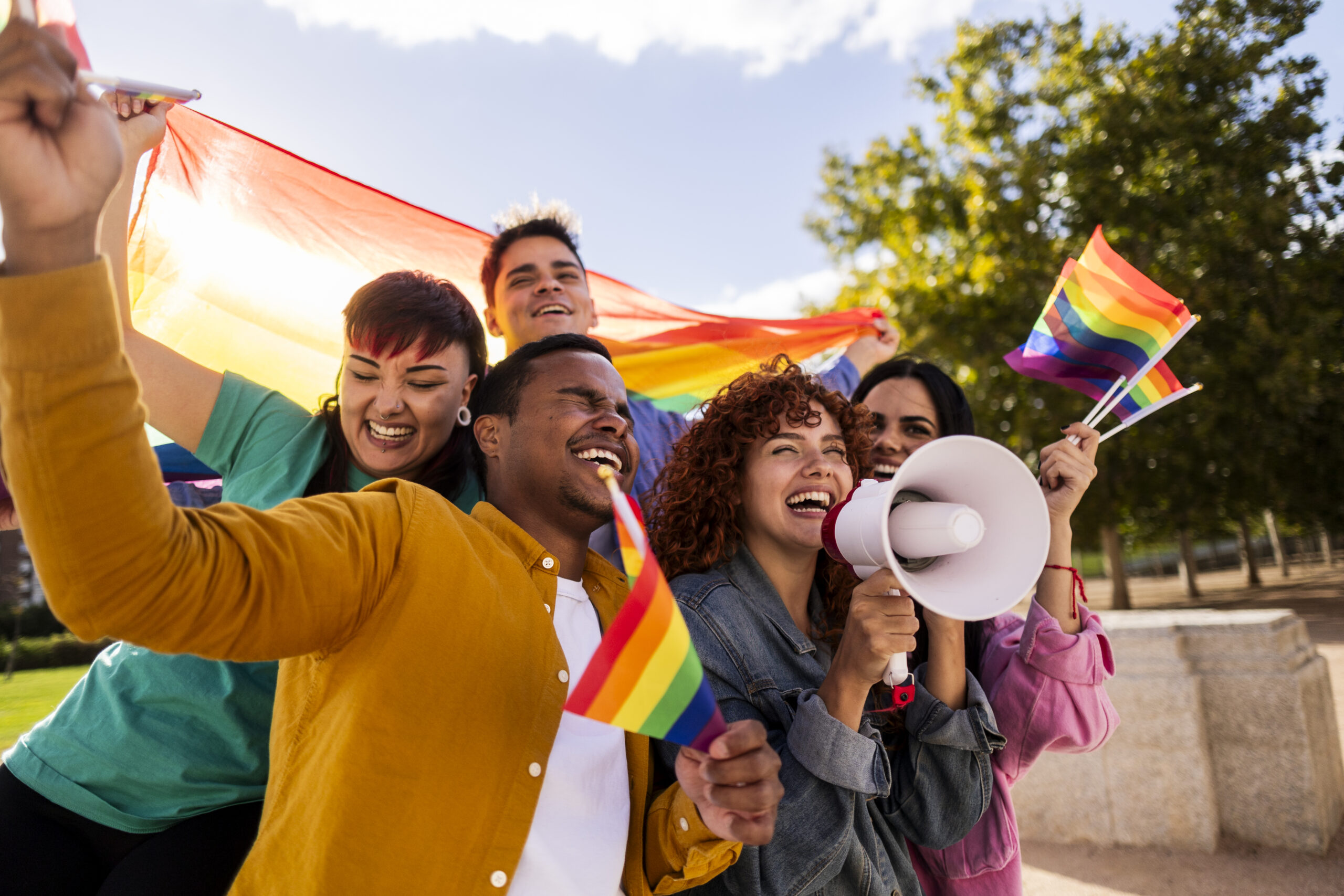 Happy activists protesting for lgbtq plus rights holding rainbow flags and megaphone